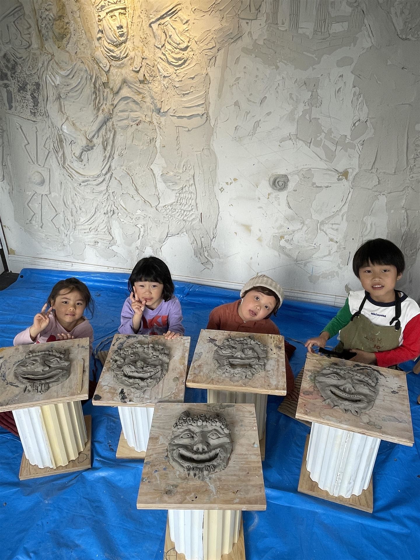 粘土でつくった古代風の仮面と子どもたち